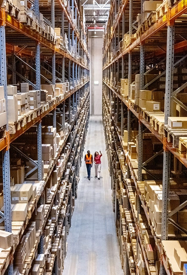 Well-organized high-bay warehouse with many packages and two employees