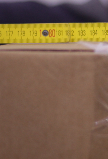 Ein Karton auf dem ein gelber Zollstock liegt