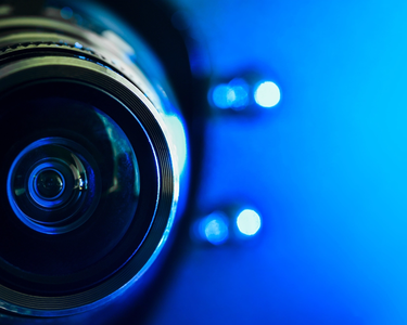Detailaufnahme einer Kameralinse mit blauem Hintergrund