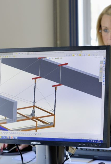 Computer mit einem Zeichungsprogramm und einer Mitarbeiterin im Hintergrund