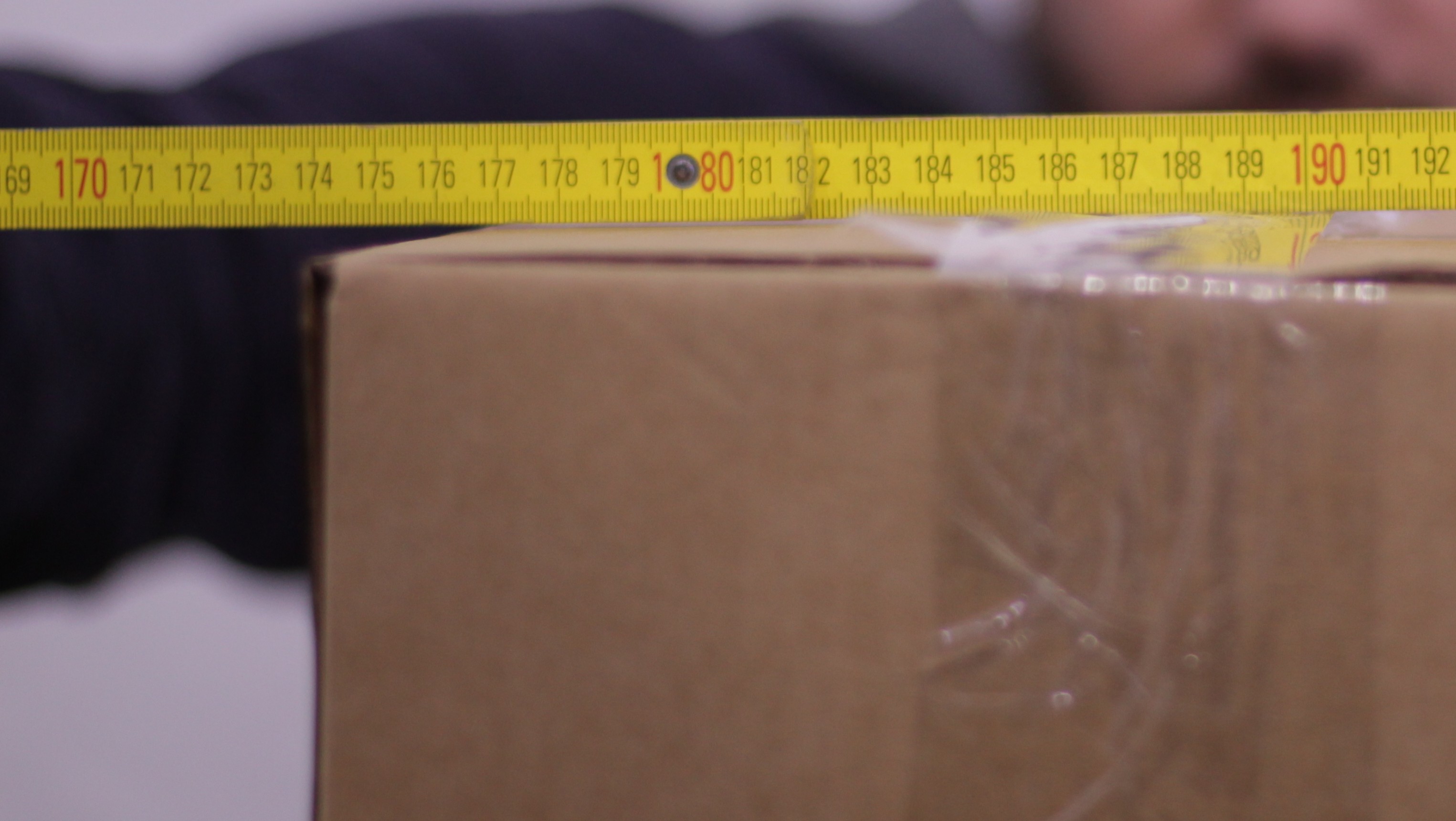 Ein Karton auf dem ein gelber Zollstock liegt