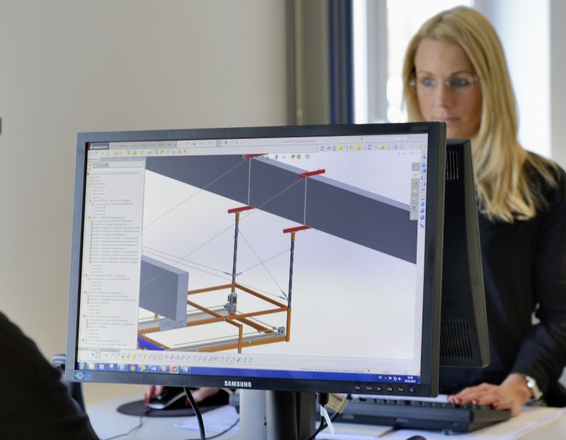 Computer mit einem Zeichungsprogramm und einer Mitarbeiterin im Hintergrund