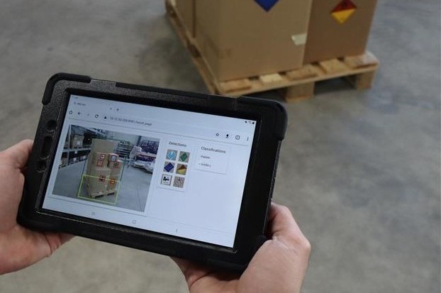 Mitarbeiter hält Tablet in der Hand und sieht Kisten und die Funktionsweise von Predictive Vision for Logistics