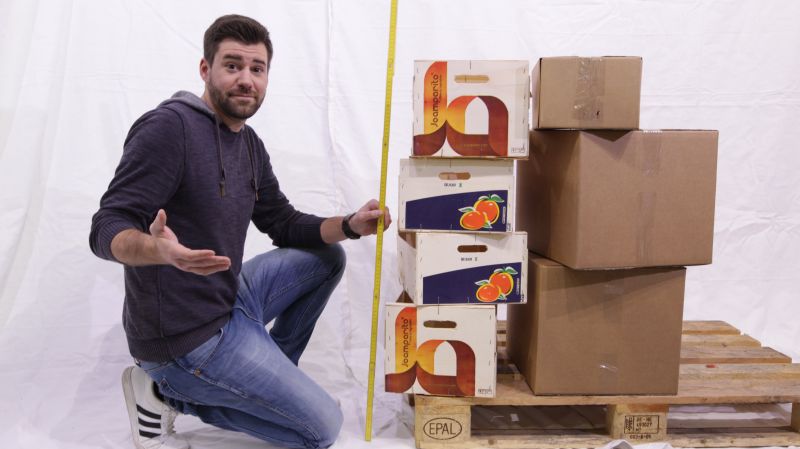 Mitarbeiter hält Zollstock neben Kartons und bestimmt die Höhe