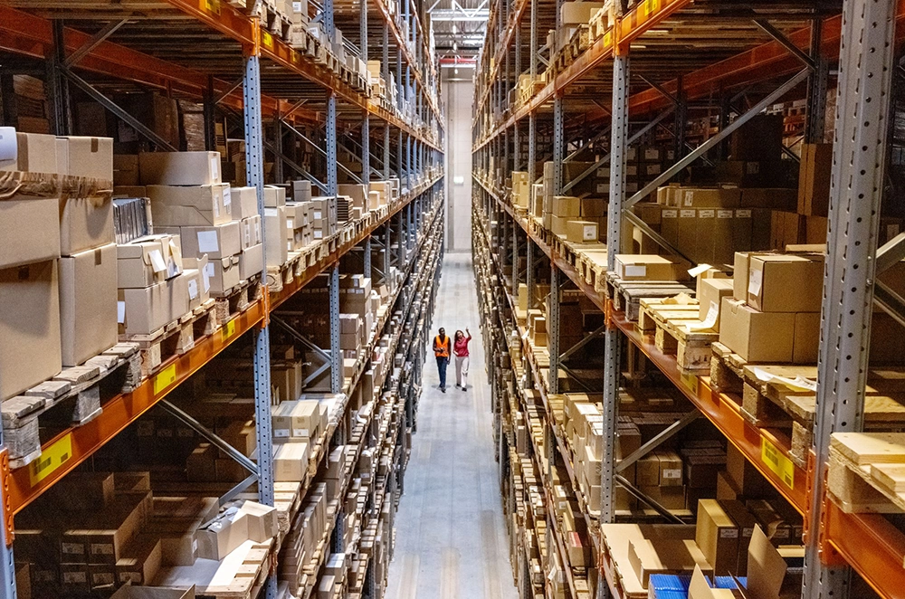 Well-organized high-bay warehouse with many packages and two employees